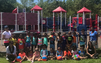 Students with Beach Balls in Front of a Playground