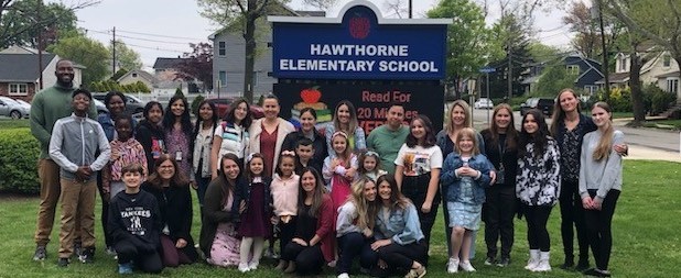 Teachers and their Children Standing in Front of a Sign