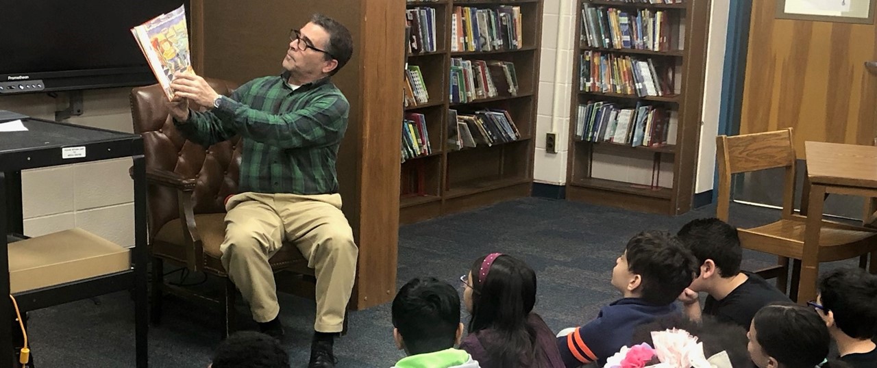 Principal Reading to a Group of Students