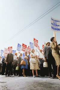 Demonstrators marching in the street holding signs saying "Freedom" during the March on Washington, 1963