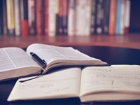 Two open books on a tabletop with a library background.